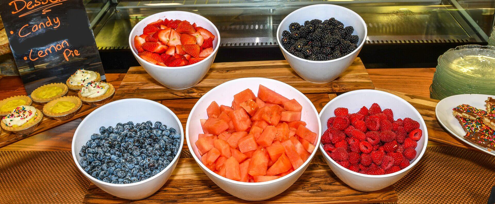 A wooden table topped with bowls of fruit.