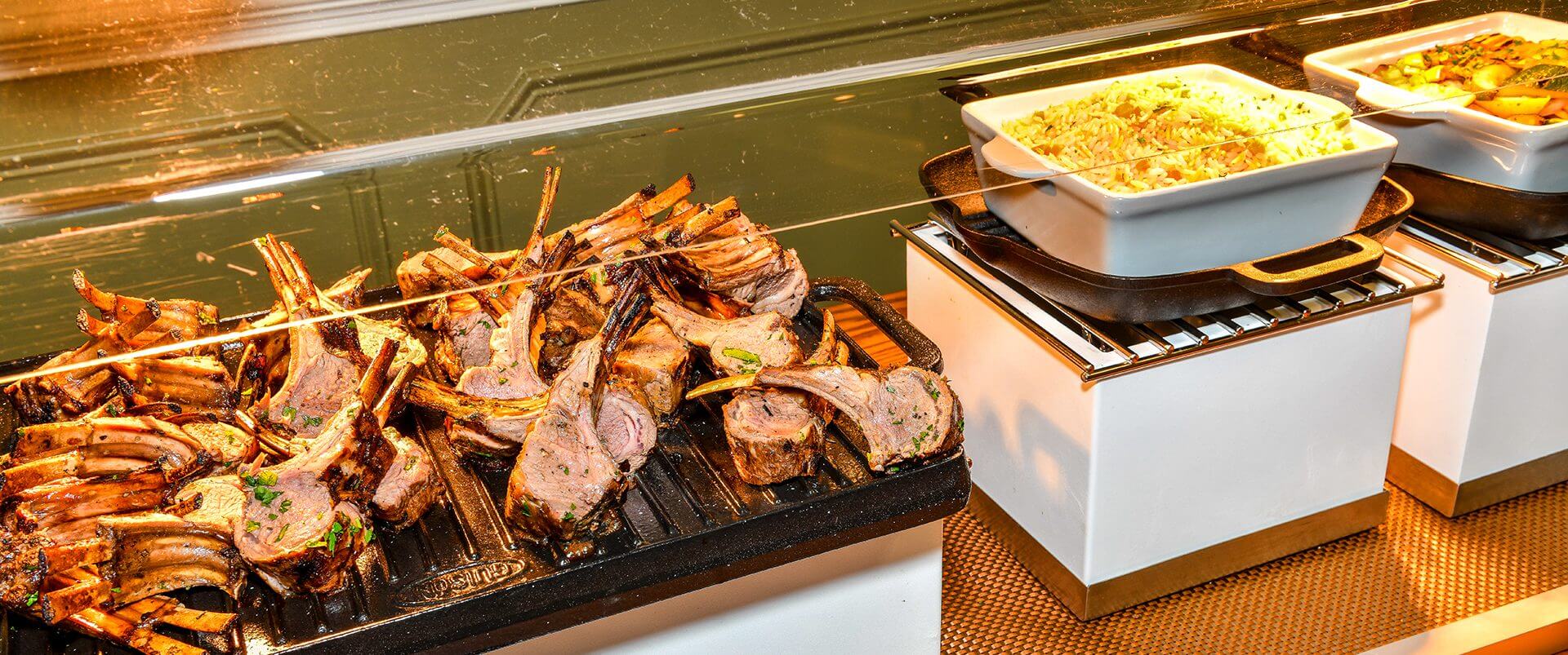 A grill with some meat on it and a pan of food