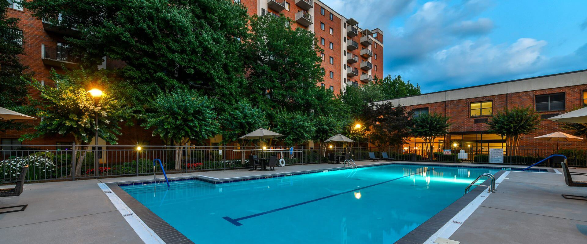 A pool with umbrellas and chairs in the background.