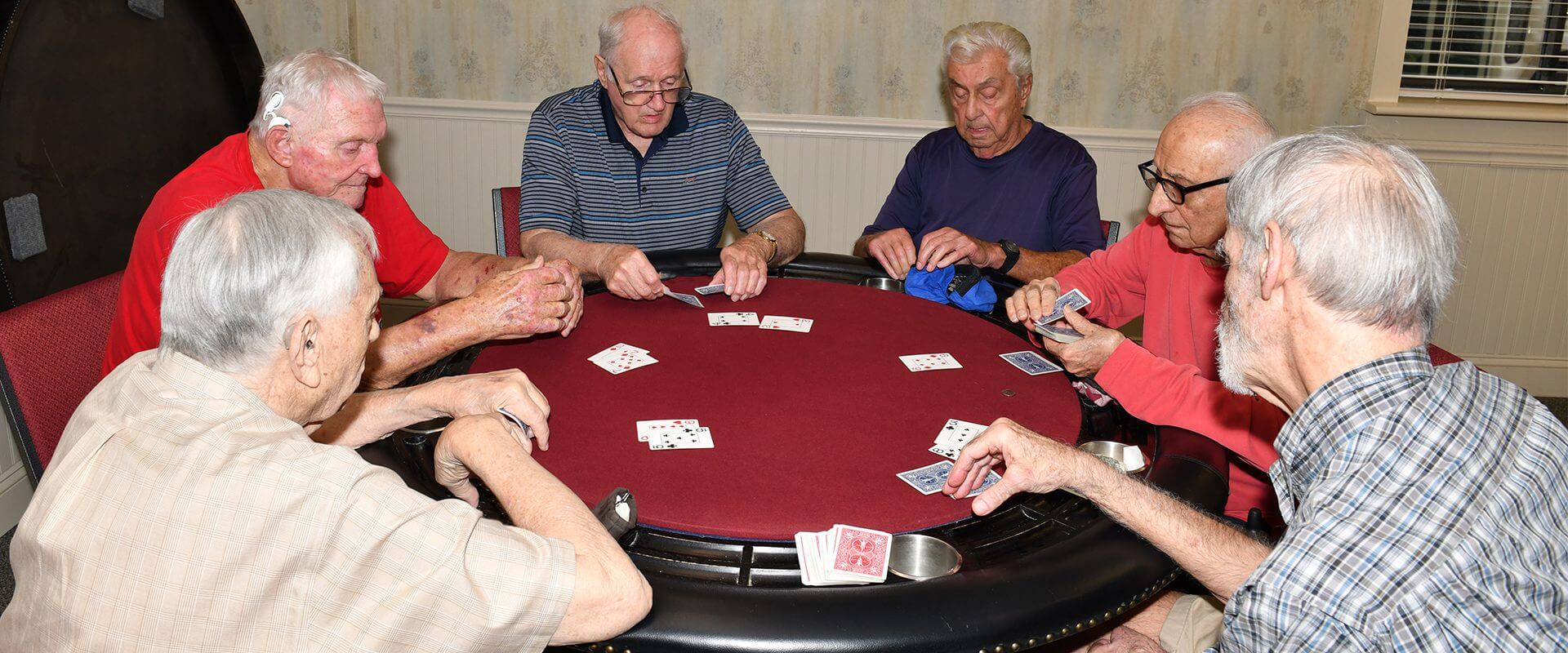 Elderly men playing poker around table