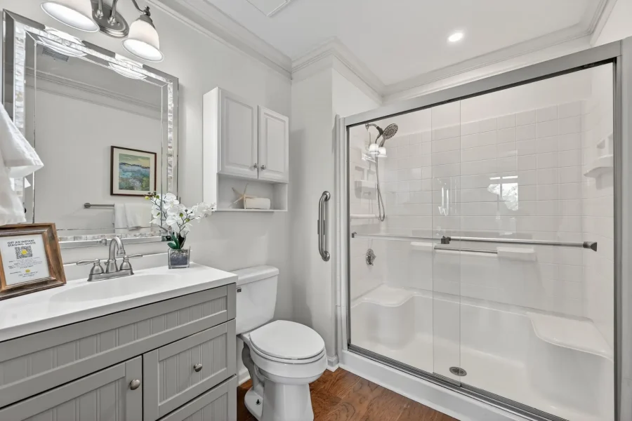 Contemporary bathroom with a glass-enclosed shower, gray vanity, and toilet.