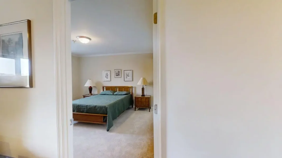 View into a hotel-style bedroom with a wooden double bed, two matching nightstands, teal bedspread, and framed art above the headboard.
