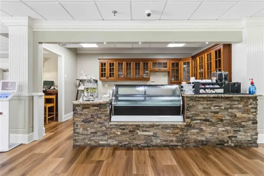 Cafe service counter with a stone facade, glass display case, and wooden cabinets behind; coffee equipment visible on the right.