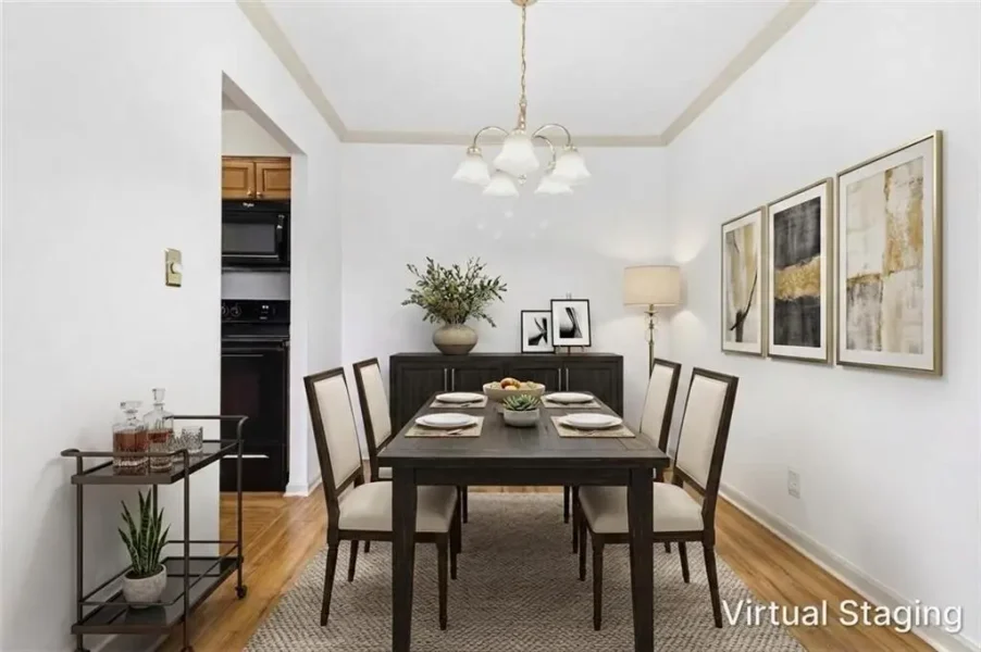 Six-seat dining room with a dark wooden table, beige upholstered chairs, a chandelier, and a sideboard against the back wall with plants nearby.